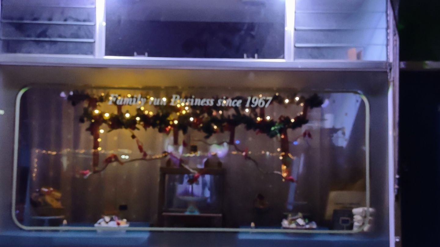 The shop window at night: "Family run Business since 1967" lettered across the glass above a garland of fairy lights